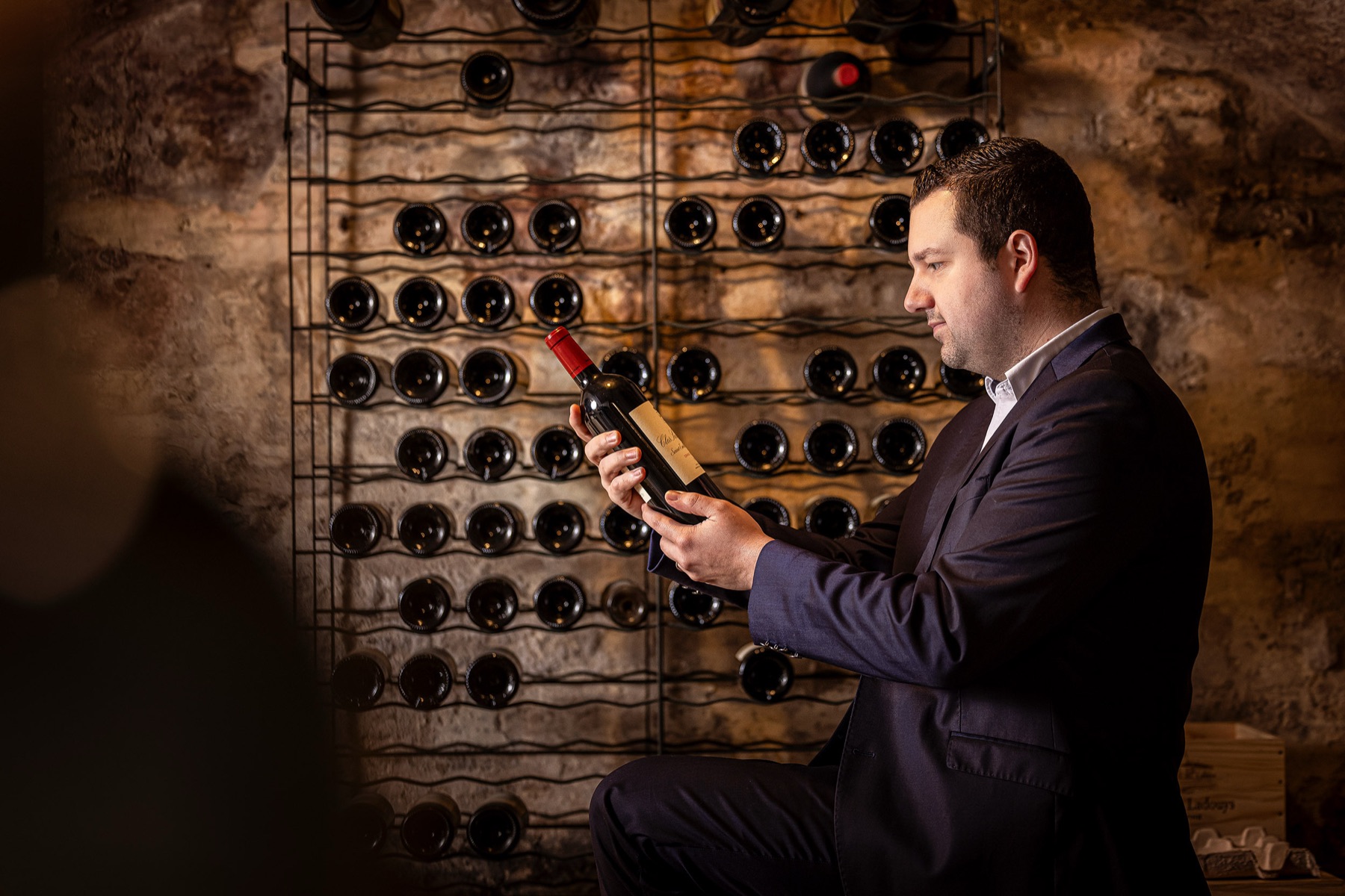 Sebastien bekijkt een fles in de wijnkelder